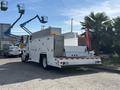 A 2006 International 4300 truck with a white body and multiple compartments for storage parked on a driveway