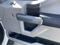 A close-up of the interior door panel of a 2018 Ford F-150 showing the armrest and speaker area with a textured surface and control buttons