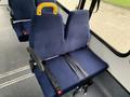 A blue upholstered seat from a 2015 Chevrolet Express with a yellow grab handle and black seatbelt secured in place