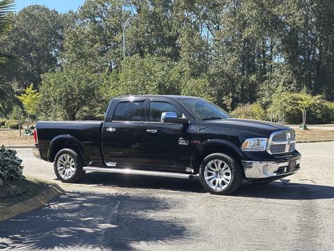 A black 2015 RAM 1500 pickup truck with chrome accents and shiny wheels parked on a paved surface