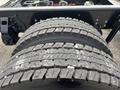 Close-up of a dual tire setup on a heavy-duty vehicle with deep tread patterns and visible wear on the rubber surface