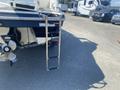 A metallic swim ladder attached to the back of a 2013 Larson 238 boat showing five steps and a secure mounting structure