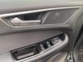Close-up of the interior door panel of a 2017 Ford Edge featuring a door handle speaker grille and window control buttons