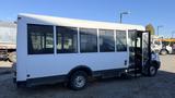 A white 2021 Ford Transit bus with a large door open on the side showcasing its interior features and seating arrangement
