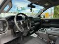 Interior view of a 2019 Chevrolet Silverado 1500 featuring a black steering wheel with a silver emblem various controls on the dashboard and a central console with cup holders