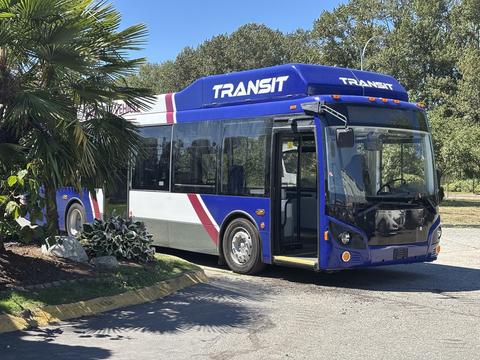 A 2018 Grande West Vicinity bus in blue and white with red accents displaying the word TRANSIT on the front and side with its door open