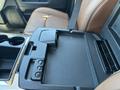 Interior view of a 2015 RAM 1500 featuring a console with cup holders and a storage compartment with a textured surface
