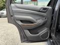 A 2017 Chevrolet Tahoe door panel featuring gray leather upholstery with wood trim accents and integrated controls for windows and locks