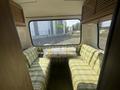Interior of a 1976 GMC Motorhome featuring two plaid sofas and a table with a wrapped item in the center