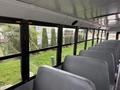 Interior of a 2022 Freightliner B2 school bus showing empty gray seats and large windows with a view outside