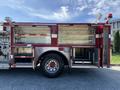 A red 1992 Emergency One Typhoon Superior fire truck with open storage compartments and emergency lights on top