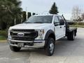 A 2020 Ford F-550 truck with a flatbed design is parked at an angle showcasing its front and side features