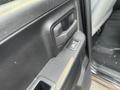 Close-up of the interior door handle and control buttons of a 2015 RAM 1500 with a textured black finish and a cloth seat visible through the open door