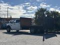 A white 2014 RAM 5500 flatbed truck parked with a wooden bed and black rear panels