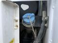 A blue cap on a fluid reservoir with a metal wire attached, part of the engine compartment of a 2012 Global M4