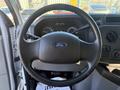 The steering wheel of a 2019 Ford E-450 featuring the Ford logo in the center and control knobs and gauges visible in the background