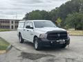 A white 2016 RAM 1500 pickup truck parked with a black front grille and a utility shell in the cargo area