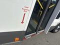 A 2018 Chevrolet Express bus with a sign indicating a ramp and kneeling feature positioned near the open door