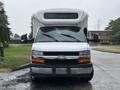 A white 2018 Chevrolet Express van with a large camper shell on top facing forward