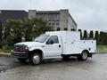 A white 2000 Ford F-450 truck with a utility box on the back and a flatbed is parked on a wet surface