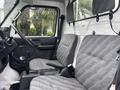Interior of a 2010 Suzuki Carry showing two gray fabric seats and a simple dashboard with controls and gear shift