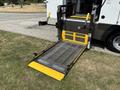 A wheelchair lift with a metal platform and yellow markings extending from the side of a 2020 Chevrolet Express van