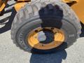 A large tire from a 2016 Case 580 Super N featuring deep treads and a yellow rim with visible branding on the sidewall