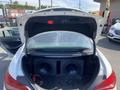 A 2014 Mercedes-Benz CLA-Class with an open trunk showcasing two large subwoofers in custom enclosures and visible wiring