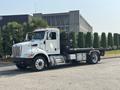 A 2020 Peterbilt 330 truck with a flatbed body featuring side rails and an open cargo area is parked on a paved surface