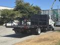 A 2011 International 4300 flatbed truck with a black metal bed and side rails parked in a lot