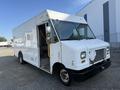 A white 2012 Ford Econoline cargo van with a large rear cargo area and a step at the front door showcasing its open entryway