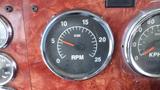 Close-up of a tachometer gauge showing RPM readings from 0 to 25 with a needle positioned at 5 on a dashboard of a 2003 International 5600i truck