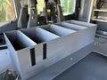A gray organizational box with four compartments sits on a flat surface inside a vehicle