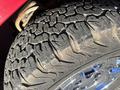 Close-up of a rugged tire with deep treads on a shiny wheel of a 2011 Chevrolet Avalanche showing dirt and wear on the rubber surface