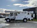 A 2011 International 4300 bucket truck with a raised aerial lift and white storage compartments on the side