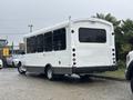 A 2018 Chevrolet Express bus with a white exterior and large windows parked with its rear facing the viewer