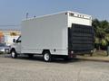 A 2008 Ford Econoline box truck with a silver body and a black roll-up door at the rear is parked on a paved surface