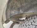 Close-up of a 2022 GMC Savana’s wheel well and tire showing the rugged texture of the tire tread and the undercarriage components