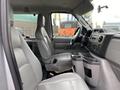 Interior of a 2010 Ford Econoline showing gray seats and dashboard with controls and cup holders visible