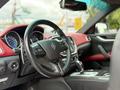 Interior of a 2016 Maserati Ghibli featuring a red leather steering wheel and dashboard with modern controls and gauges