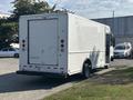 A white 2012 Ford E-450 box truck with rear roll-up door and red taillights parked in a lot