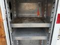 An empty metal cargo box with two shelves inside showing a metallic interior and some signs of wear and rust