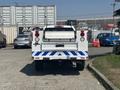A 2017 Chevrolet Colorado with a white body and blue stripes on the rear bumper is parked with tailgate down and lights illuminated