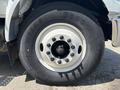 Close-up of a white wheel with a large tire and multiple black lug nuts on a 2015 Ford F-750