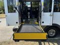 A 2020 Chevrolet Express with an extended wheelchair lift at the rear entrance featuring a yellow mesh platform and handrails for accessibility