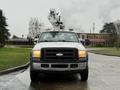 A 2006 Ford F-450 pickup truck with a raised aerial work platform mounted on the bed designed for overhead tasks