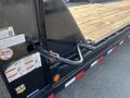 Close-up of a 2020 Load Trail 28 Foot Gooseneck trailer featuring a dark frame and wooden flooring with various safety labels and a hitch on the side