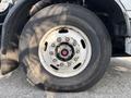 A close-up of a large tire mounted on a wheel with a central red hub and multiple metal bolts securing it to the wheel rim