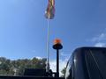 A 2022 Ford F-350 SD equipped with an orange beacon light and a flag mounted on a pole attached to the truck's back
