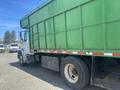 A 1997 Freightliner FL70 truck with a large green dump body and a white cab is parked with visible wheels and a steel frame near the rear.